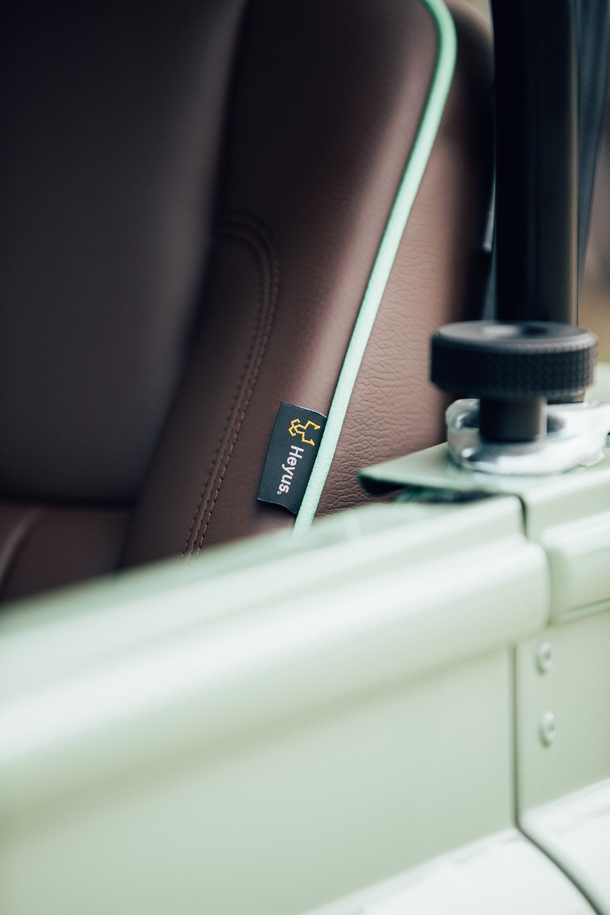 A close-up detail shot of the interior of a finished, light green vehicle, likely a Series or Defender. The focus is on a small, black fabric tag…