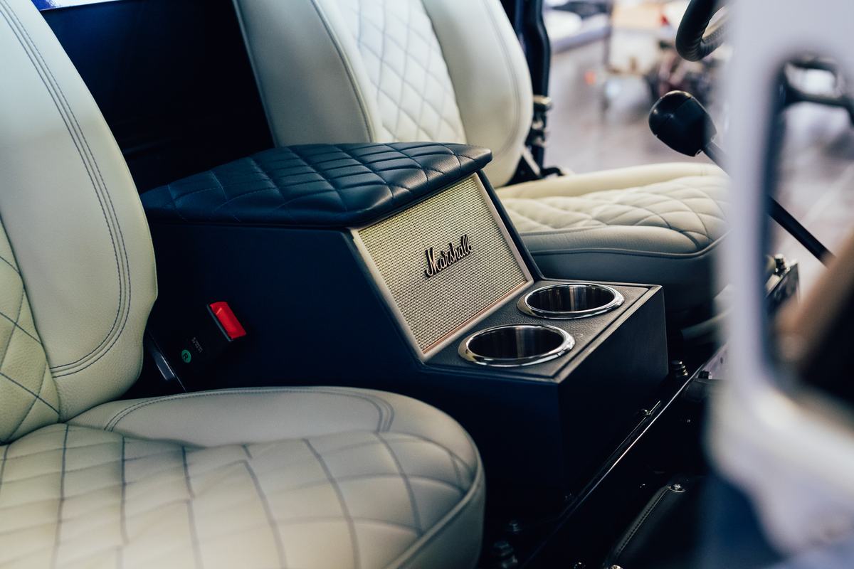 A close-up interior shot of a finished Land Rover, focusing on the centre console. The console is custom-made, featuring a black quilted leather…