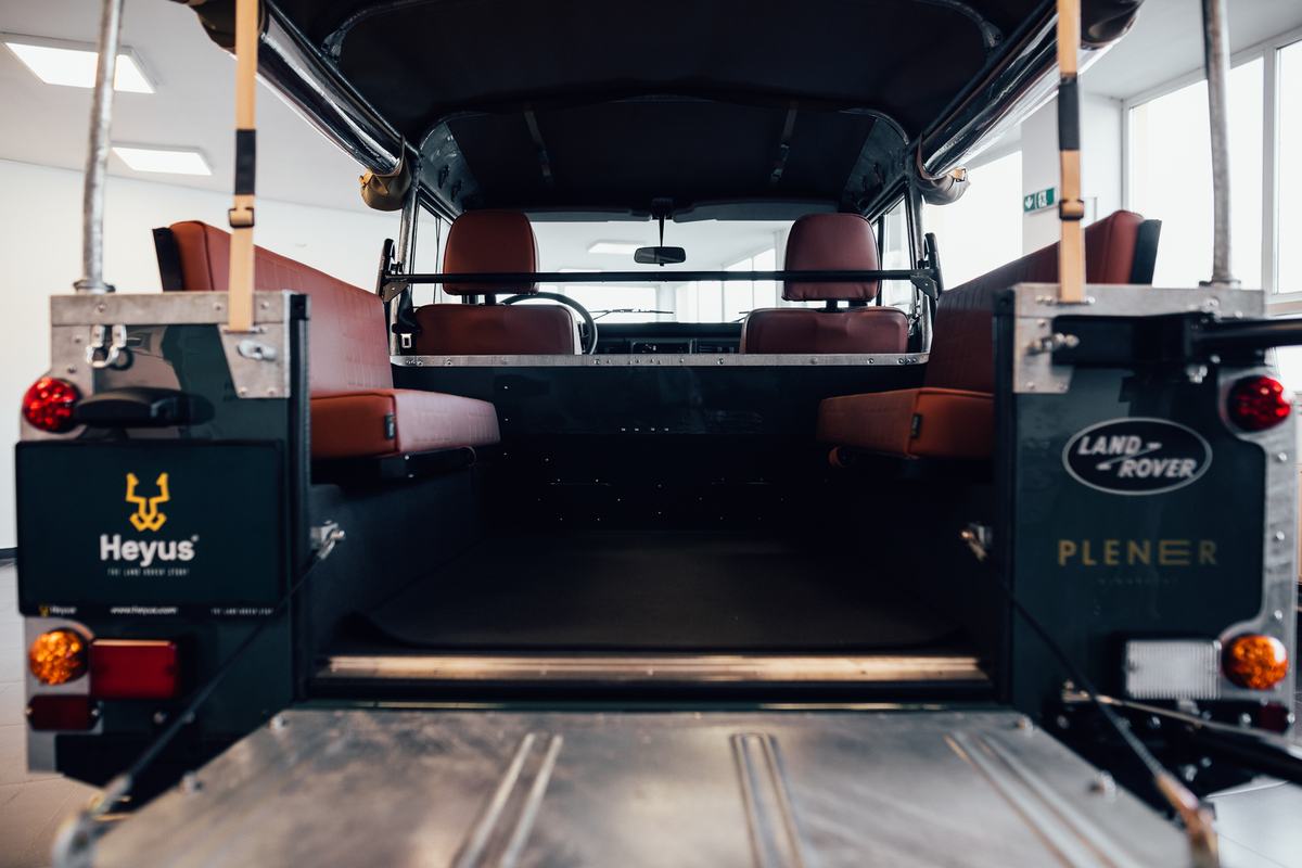 View through the open rear doors of a restored Land Rover Defender/Series, looking forward through the empty load bay toward the front seats and dashb…