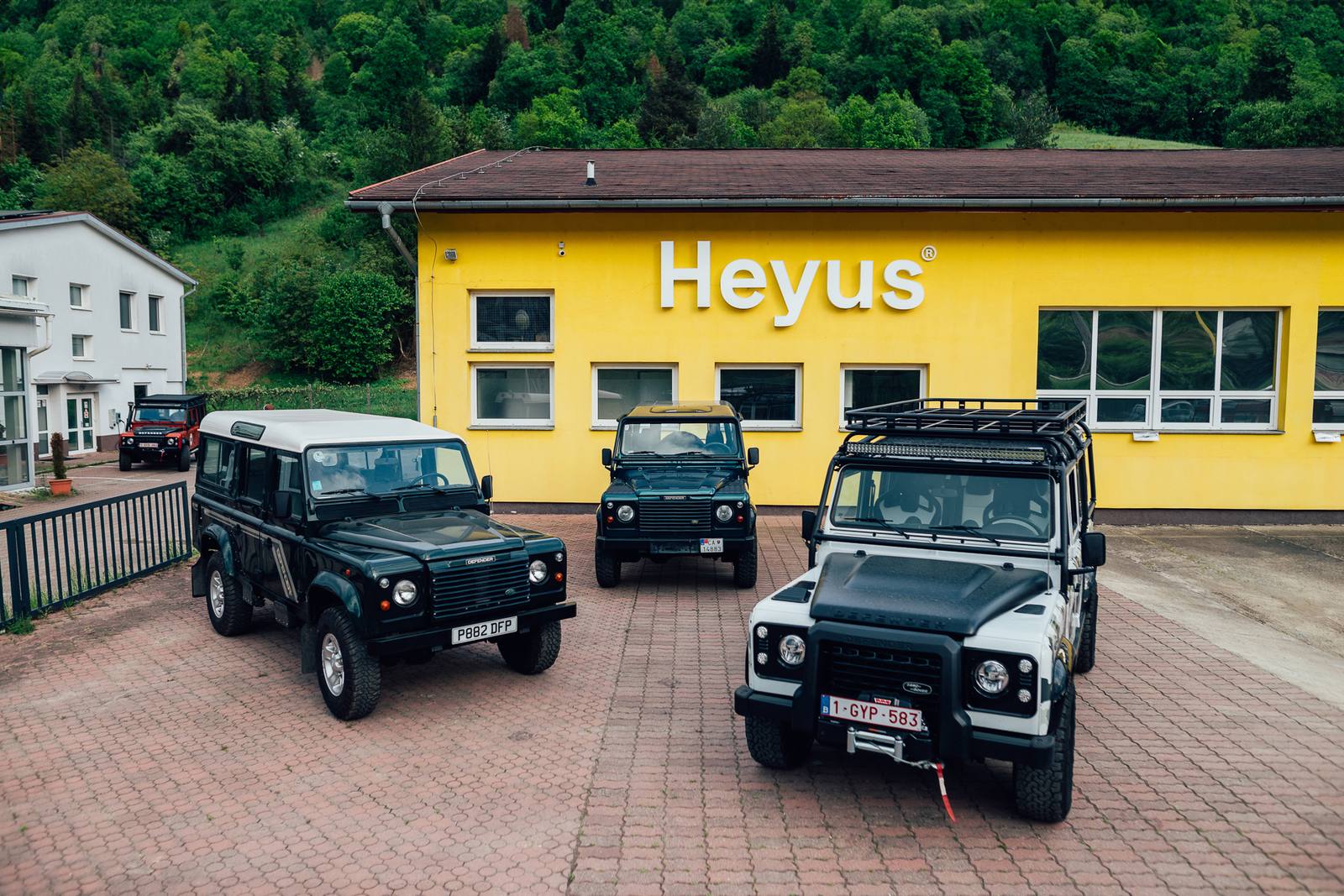 Dielňa Heyus — žltá budova s nápisom Heyus a tri Defendery na dvore